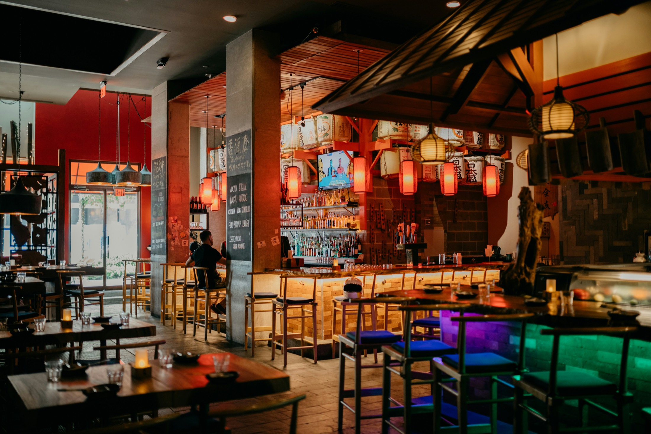 A warm izakaya-style Japanese restaurant interior hung with red paper lanterns